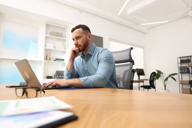 Ofiste dizüstü bilgisayarda çalışan adam, düşük açılı görünüm.