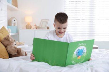 Yatma vakti. Yatakta kitap okuyan sevimli çocuk.