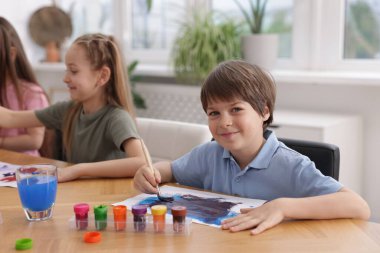 Çocuklar kapalı mekanlarda resim yapıyor, seçici bir odak noktası var. Çizim yapmayı öğrenmek