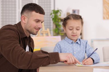 Çocuğa resim dersinde resim çizmeyi öğreten bir adam.