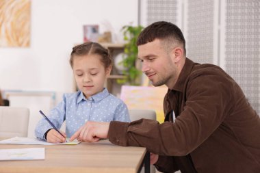 Çocuğa resim dersinde resim çizmeyi öğreten bir adam.