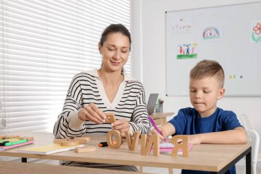 Okulda masa başında öğretmeniyle mektup öğrenen tatlı bir çocuk.