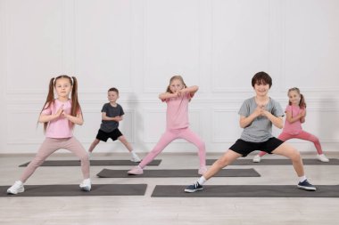 Sınıftaki minderler üzerinde yoga yapan bir grup çocuk.