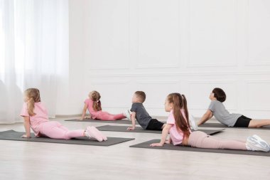 Sınıftaki minderler üzerinde yoga yapan bir grup çocuk.