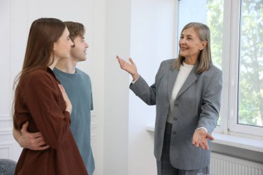 Gülümseyen emlakçı evde çiftlerle çalışıyor.