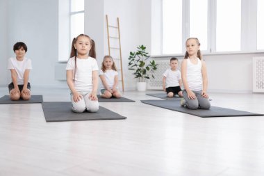 Sınıfta yoga minderleri üzerinde bir grup çocuk.