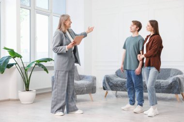 Tabletle gülümseyen emlakçı evde çiftlerle çalışıyor.