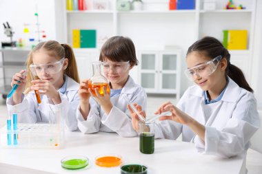 Çocuklar içeride masada kimyasal deneyler yapıyorlar.