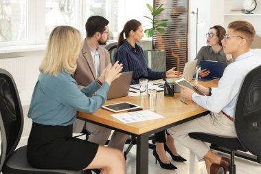 Ofisteki ahşap masada birlikte çalışan iş arkadaşları.