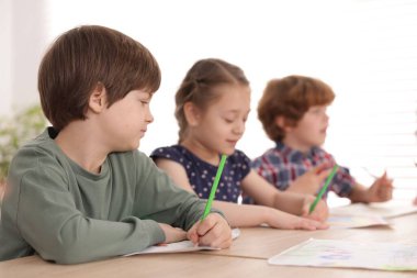 Çocuklar kapalı mekanlarda resim yapıyor, seçici bir odak noktası var. Çizim yapmayı öğrenmek