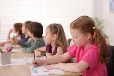 Çocuklar kapalı mekanlarda resim yapıyor, seçici bir odak noktası var. Çizim yapmayı öğrenmek