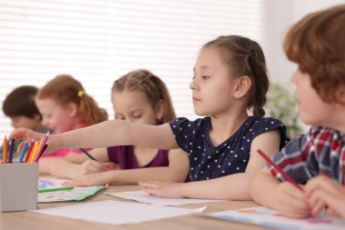 Çocuklar kapalı mekanlarda resim yapıyor, seçici bir odak noktası var. Çizim yapmayı öğrenmek