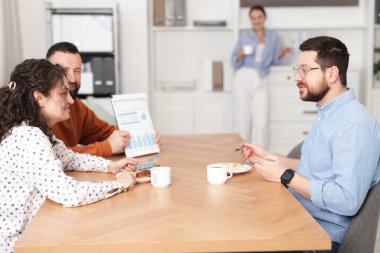 İş arkadaşları yemek yiyor ve ofiste öğle arasında iş tartışıyorlar.