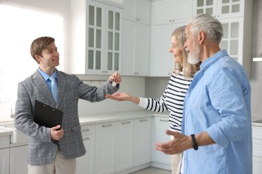 Gülümseyen emlakçı, mutfağın yeni sahibine evinin anahtarını veriyor.