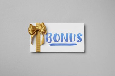 Gri arka planda altın fiyonklu bonus kart, üst manzara