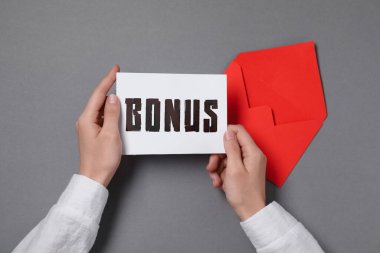 Gri masada elinde kelime bonusu olan bir kadın var.