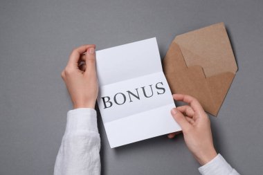 Gri masada elinde kelime bonusu olan kadın, üst manzara.