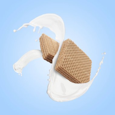 Lezzetli gevrek gofretler ve açık mavi arka planda sütü sıçratma