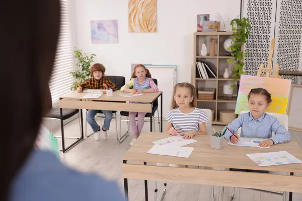Çocuklara resim yapmayı öğreten kadın kapalı alanda resim dersi veriyor, seçici bir odak.