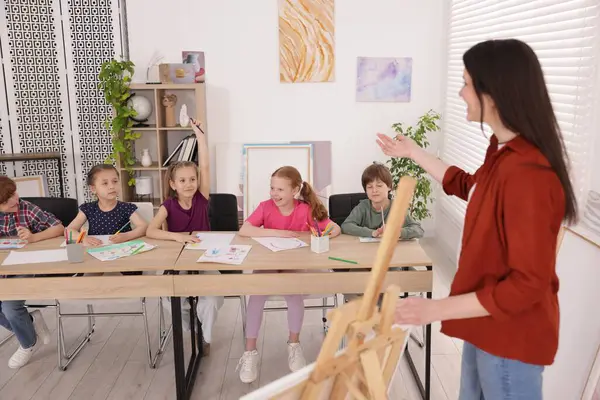 Çocuklara resim dersinde resim öğreten bir kadın.