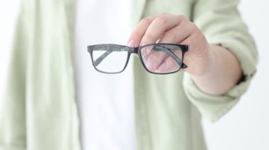 Beyaz arkaplanda bir çift gözlük gösteren kadın, yakın plan