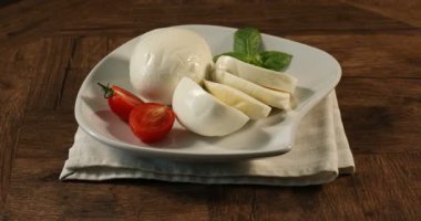 Lezzetli mozzarella, domates ve fesleğen ahşap masada dönüyor, yakın plan.