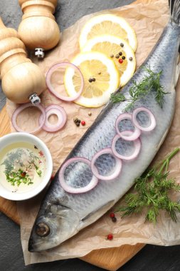 Lezzetli ringa balığı, siyah masada baharatlar, düz uzanmış.