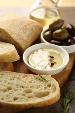 Ahşap masada yağlı, zeytinli ve baharatlı dilimlenmiş ekmek, yakın plan.