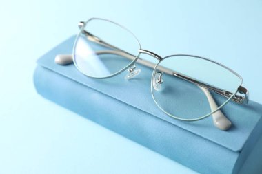 Açık mavi arka planda şık gözlüklü çanta, yakın plan