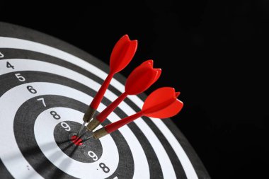 Hedef alınıyor. Siyah arkaplanda okları olan dart tahtası, yakın plan