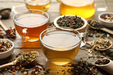 Tahta masada farklı bitki çayları ve kuru yapraklar, yakın plan.