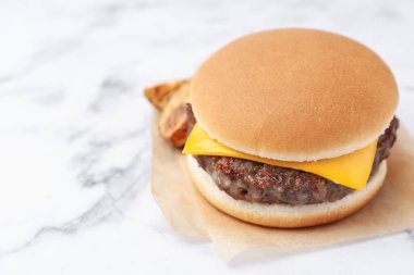 Beyaz mermer masada patates dilimleri olan lezzetli bir çizburger, yakın plan. Metin için boşluk