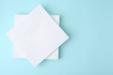 Açık mavi arka planda tek kullanımlık kağıt mendil yığını, üst manzara. Metin için boşluk