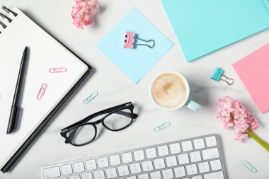 Beyaz mermer masa üzerinde kırtasiye, çiçek ve kahve ile düz kompozisyon yatıyordu