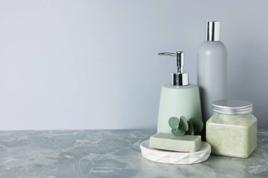 Gri mermer masada farklı banyo aksesuarları ve okaliptüs dalları, yakın plan. Metin için boşluk