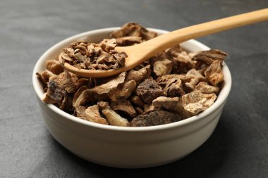 Kuru hindiba kökleri kasede ve kaşıklar karanlık masada, yakın plan.