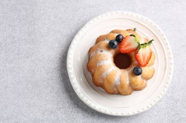 Açık gri masada pudra şekeri ve böğürtlenli Lezzetli Bundt keki, üst manzara. Metin için boşluk