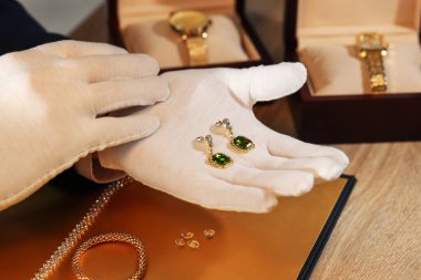 Masada lüks küpelerle çalışan eksper, yakın plan.