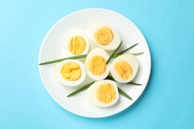 Açık mavi arkaplanda haşlanmış yumurta ve yeşil soğan, üst manzara.