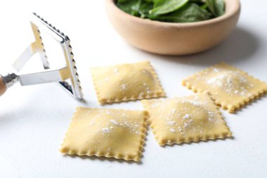 Pişmemiş ravioli, keski ve ıspanak beyaz masada, yakın plan.