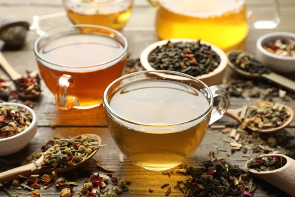 Tahta masada farklı bitki çayları ve kuru yapraklar, yakın plan.