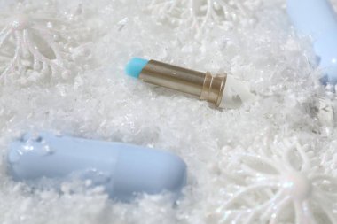 Nemlendirici dudak kremleri ve yapay kar üzerine Noel dekoru, yakın plan. Kış bakımı