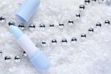 Nemlendirici dudak kremi ve yapay karla süslenmiş Noel süsü. Kış bakımı