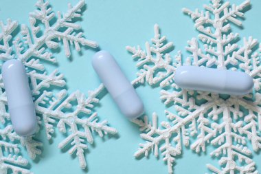 Nemlendirici dudak kremi ve açık mavi arka planda Noel dekoru, düz yatış. Kış bakımı