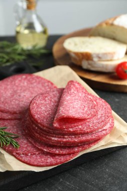 Lezzetli füme sosis ve biberiye dilimleri siyah masada, yakın plan.