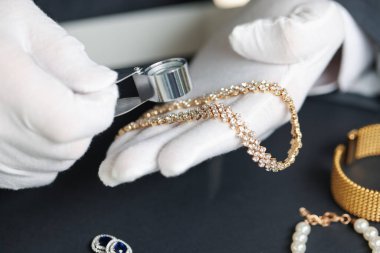 Masadaki lüks mücevherleri değerlendiren eksper, yakın plan.