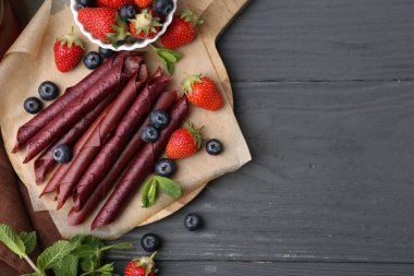 Lezzetli meyve dürümleri, çilekler, yaban mersinleri ve nane şekeri gri ahşap masa, düz yatak. Metin için boşluk