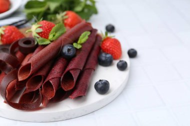 Lezzetli meyve dürümleri, çilekler, yaban mersini ve nane şekeri beyaz fayanslı masada, yakın plan.