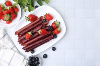 Lezzetli meyve dürümleri, çilekler, yaban mersinleri ve nane şekeri beyaz fayanslı masa, düz yatak. Metin için boşluk