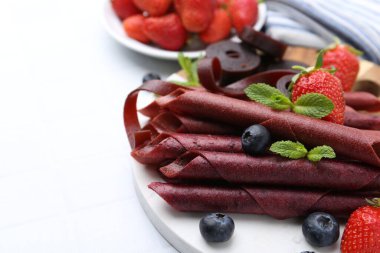 Lezzetli meyve dürümleri, çilekler, yaban mersini ve nane şekeri beyaz masada, yakın plan. Metin için boşluk